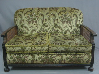 A  1930's oak framed single cane Bergere suite with 2 seat  settee and 2 matching armchairs, raised on bun feet