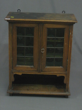 An  Edwardian walnut smoker's cabinet, the interior shelved  and fitted  a  drawer  enclosed  by a  lead  glazed  panelled  door  20"