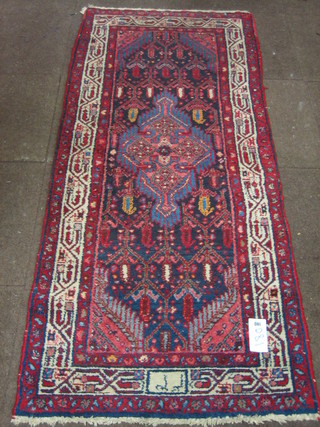 An Eastern red ground rug with central geometric medallion  73" x 32", signed