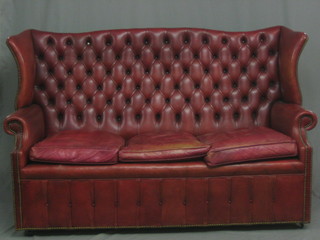 A  Victorian  style  winged high back  settee  upholstered  in  red buttoned back leather 73"