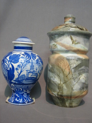 A  Soviet Russian pottery jar and cover decorated birds amidst  a wooded  landscape  13"  and a blue and white  jar  and  cover  9"