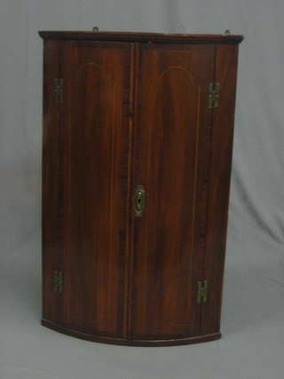 A  Georgian  mahogany  bow front  corner  cabinet,  the  interior fitted  adjustable  shelves,  enclosed  by  a  panelled  door   inlaid  satinwood and ebony stringing 24"