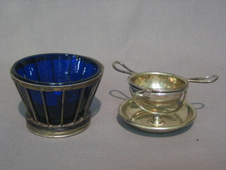 A  silver  plated  salt of circular railed form  complete  with  blue glass liner and a silver plated tea strainer