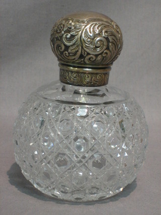 A cut glass globular shaped scent bottle with embossed silver lid