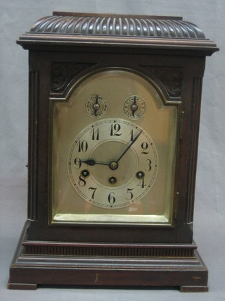 A 19th Century chiming bracket clock with arch shaped silvered dial with Arabic numerals, contained in a carved mahogany case