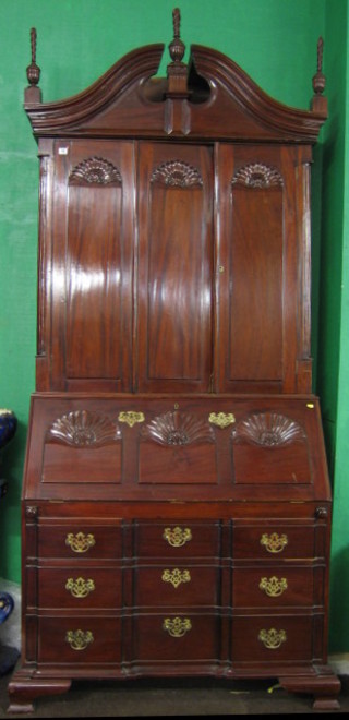 A 20th Century Queen Anne style mahogany bureau bookcase, the upper section with broken pediment, the interior fitted various pigeon holes enclosed by panelled doors, the base with fall front revealing a well fitted interior above 3 long drawers, raised on bracket feet 43"