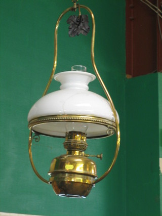 A brass hanging oil lamp with white glass shade and chimney