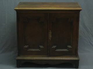 A 1930's oak Jacobean style cabinet enclosed by a panelled door, raised on bracket feet 32"