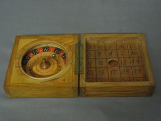 A miniature roulette wheel contained in an olive wood box, the lid incorporating various counters etc 4"