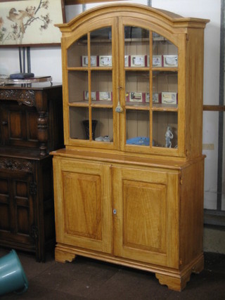 A 20th Century French style bookcase on cabinet the arch shaped top fitted shelves enclosed by a panelled door, the base fitted a double  cupboard enclosed by panelled doors, raised on bracket feet 43"