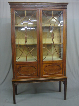 A Georgian style mahogany display cabinet with moulded and dentil cornice and blind fret work frieze, the interior fitted adjustable shelves enclosed by astragal glazed panelled doors, raised on square supports 41"