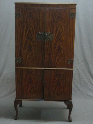 A 1950's Queen Anne style walnut cocktail cabinet enclosed by a panelled door, raised on cabriole supports 28"