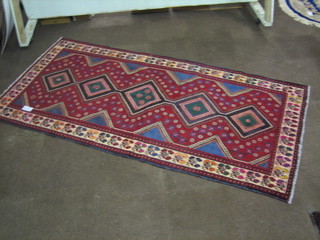 A contemporary Persian Kurdish red ground rug with 5 octagons to the centre within multi-row borders 112" x 56"