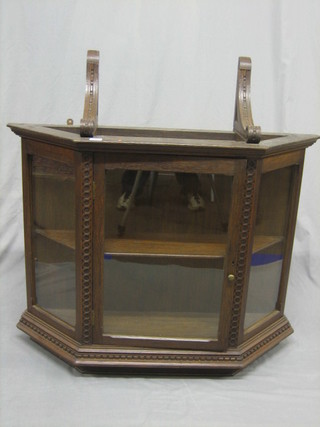 A Victorian oak hanging cabinet of lozenge form enclosed by a panelled door 38"