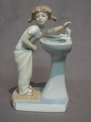A Lladro figure of a standing girl by a hand basin 7 1/2"