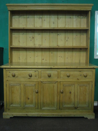 A Victorian pine dresser, the raised back with moulded cornice fitted 2 shelves, the base fitted 1 short and 2 long drawers above a double cupboard raised on a platform base 63"