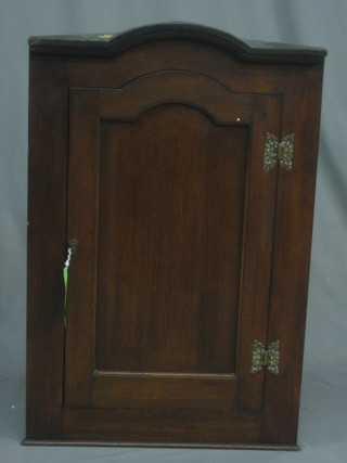 A 19th Century oak arch shaped hanging corner cabinet fitted shelves enclosed by a panelled door 23"