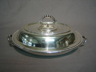 An oval silver plated twin handled entree dish and cover with bead work borders