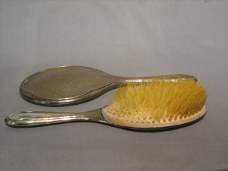 A silver backed hand mirror and matching clothes brush