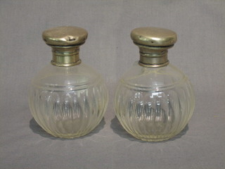A pair of circular cut glass dressing table jars of globular form with silver collars