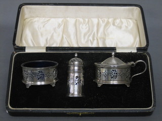 A pierced silver 3 piece condiment set  comprising salt, pepper and mustard pot, Birmingham 1927 and 1928 cased