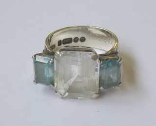 A 9ct gold dress ring set a large white square cut stone supported by 2 rectangular blue stones