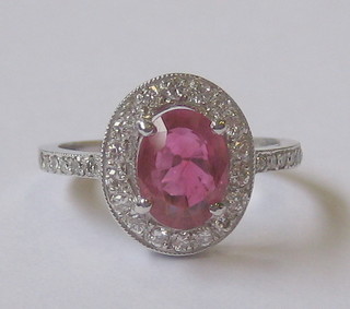 An 18ct white gold dress ring set an oval cut ruby surrounded by numerous diamonds