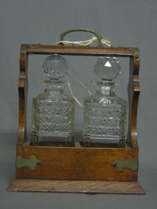 A bottle tantalus complete with 2 hobnail cut bottles contained in an oak and silver plated mounted tantalus frame