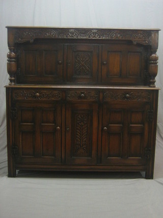 A 1930's carved oak court cupboard fitted 1 short and 2 long drawers above a double cupboard, 55"