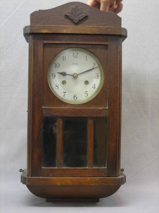 An 8 day striking wall clock with silvered dial contained in an oak case
