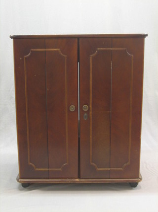 A mahogany television cabinet enclosed by panelled doors with ring mask handles to the sides 30"