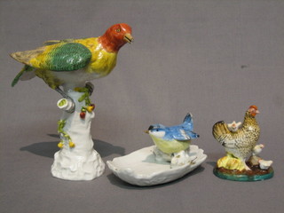 An 18th Century style porcelain figure of a seated bird (beak cracked) 7", a pin tray decorated a bluetit 5" and a 19th Century porcelain figure group of chicken with hens 3"
