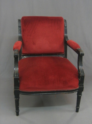 A 19th Century French black painted open arm salon chair upholstered in red material and raised on turned and fluted supports