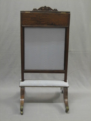A Victorian rosewood fire screen with adjustable panel, raised on scroll supports with brass caps and castors 17"