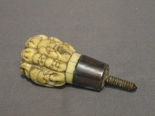 An Eastern carved ivory parasol walking stick handle in the form of numerous heads with silver band