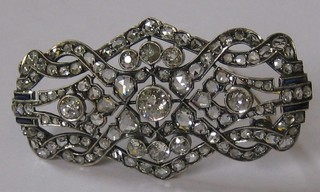 A lady's 1920's diamond set brooch, set 3 large diamonds, 4 rectangular cut sapphires and supported by numerous other diamonds