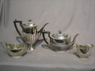 An  oval Georgian style silver plated coffee pot with demi-reeded decoration raised on circular spreading foot, together with a similar twin handled cream jug and sugar bowl and a Britannia metal teapot