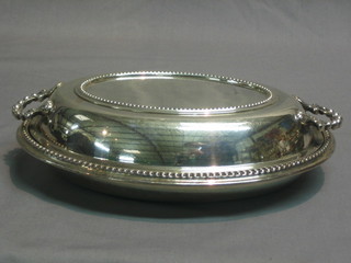 An oval silver plated twin handed entree dish and cover with bead work border