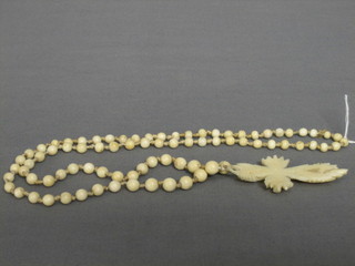 A "Dieppe" carved ivory cross hung an ivory bead chain 3"