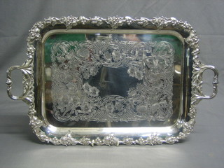 A silver plated twin handled tray with engraved decoration, raised on bun feet 17"