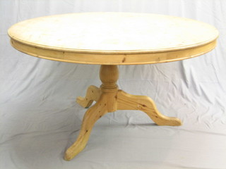 A circular pine breakfast table, raised on pillar and tripod supports 54"