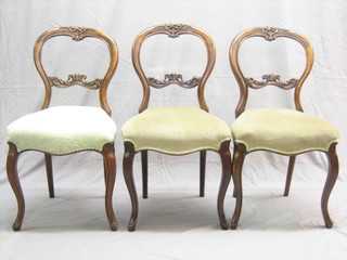 A set of 3 Victorian walnut balloon back dining chairs with carved mid rails and seats of serpentine outline, raised on cabriole supports