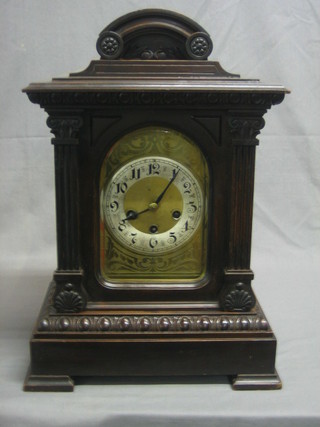 An Edwardian chiming bracket clock with arch shaped gilt dial, silvered chapter ring and Roman numerals contained in a mahogany case flanked by a pair of columns