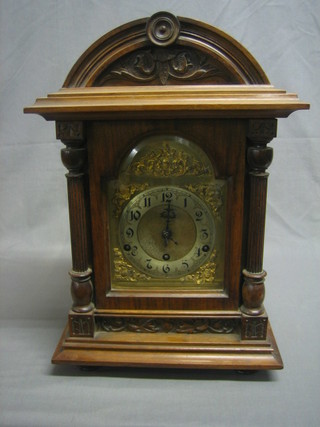 An Edwardian chiming bracket clock with arched gilt dial, silvered chapter ring and Arabic numerals contained in a walnut case