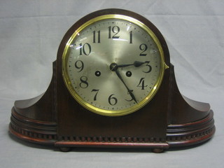 A striking mantel clock with silvered dial and Arabic numerals contained in an arched mahogany case