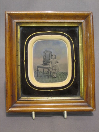 A 19th Century  black and white photograph of a standing girl by a chair, the reverse marked E Reeves, Watchmaker 59 High Street, Lewes 3" x 2" contained in a walnut frame