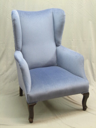 An Edwardian mahogany framed wing armchair upholstered in blue material and raised on cabriole supports