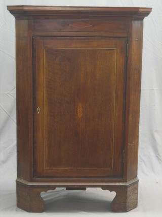 A 19th Century inlaid oak hanging corner cabinet enclosed by panelled doors, the interior fitted adjustables shelves and raised on later bracket feet 31"