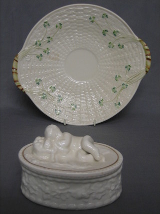 A modern oval Beleek trinket box, the lid decorated a reclining cherub 5", together with a circular twin handled plate decorated clover 9", bases with blue back and brown mark