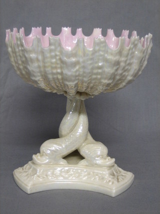 A Victorian Royal Worcester white lustre table centre piece in the form of a shell supported by 3 dolphins, raised on a triform base 7" (some chips to rim)